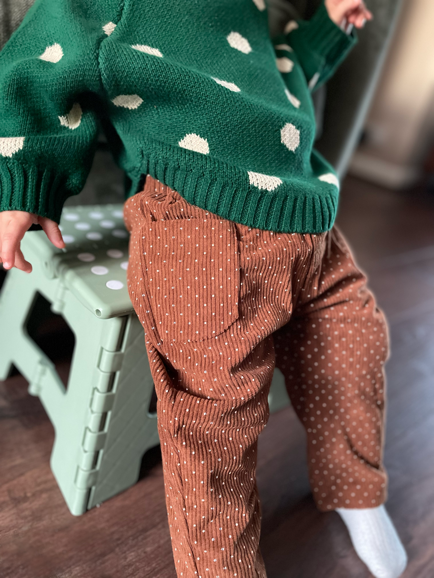 Brown corduroy baby trousers worn by toddler displays front hip pockets and relaxed fit