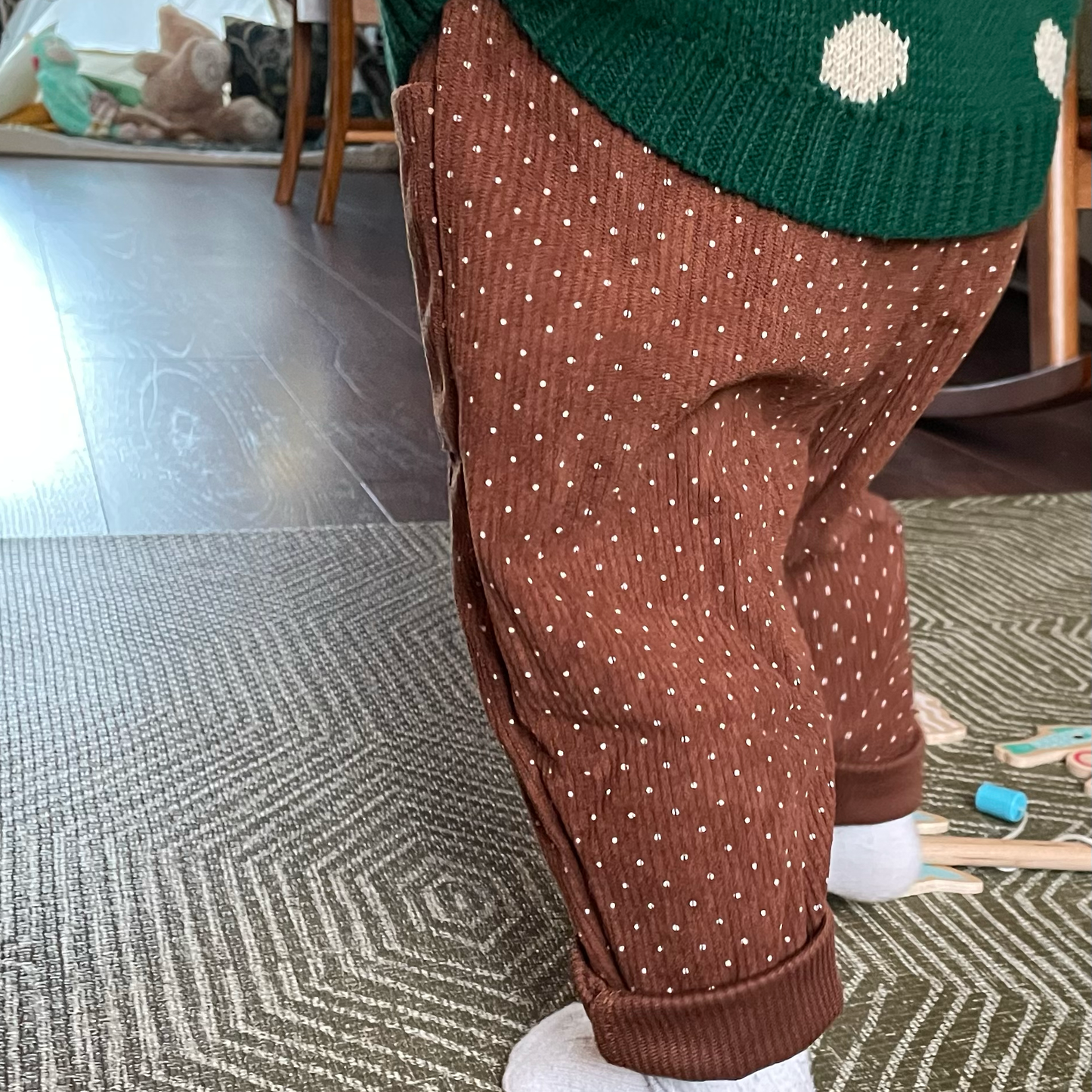 Brown corduroy baby trousers worn by toddler to show back view and loose leg fit. Rolled cuffs show how size and fit can be adapted as your baby grows.