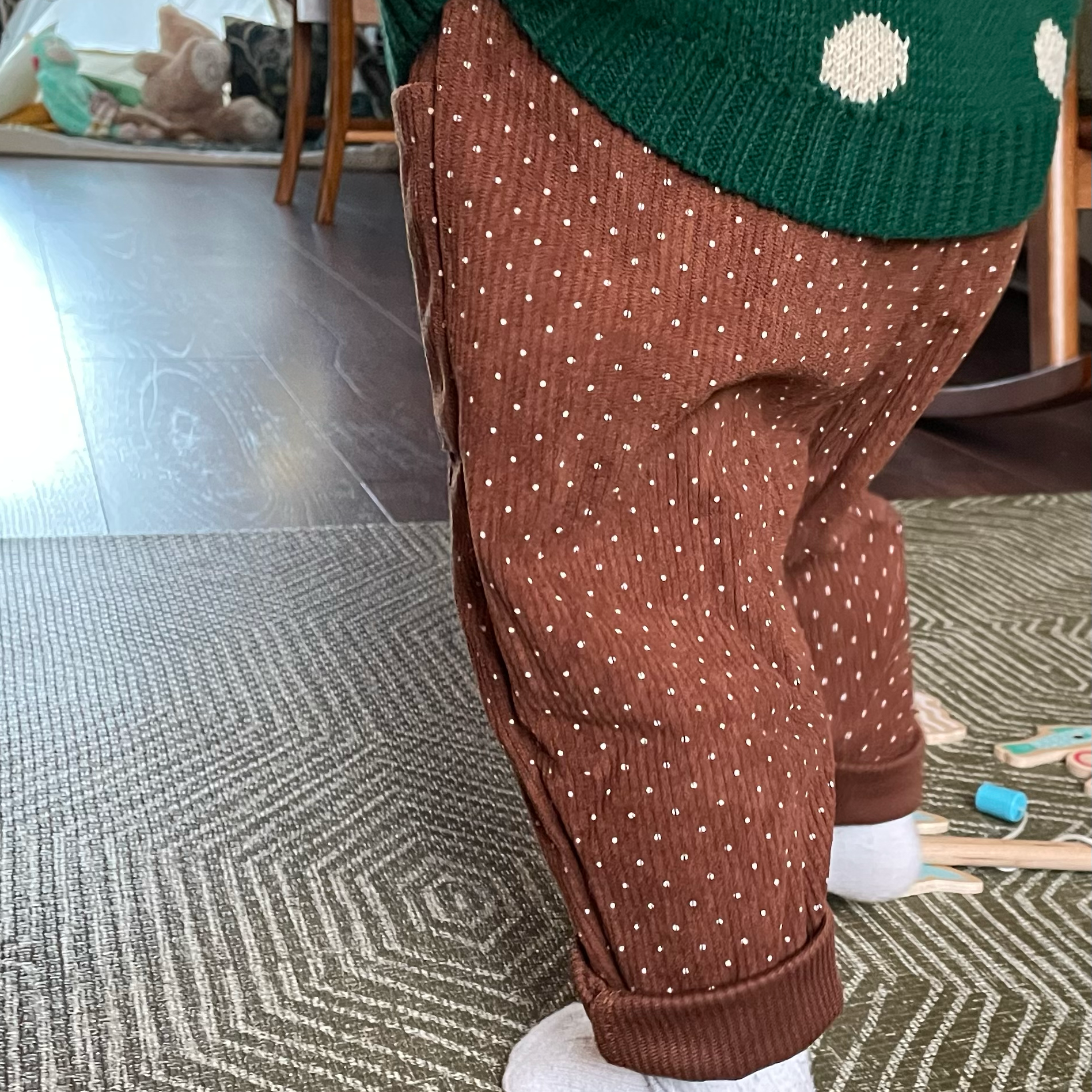 Brown corduroy baby trousers worn by toddler to show back view and loose leg fit. Rolled cuffs show how size and fit can be adapted as your baby grows.