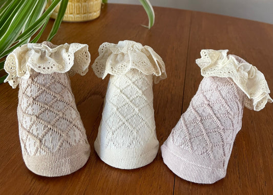 3 baby toddler socks placed on a table. One in light brown on the left, in the middle is cream, on the right is a dusty pink.