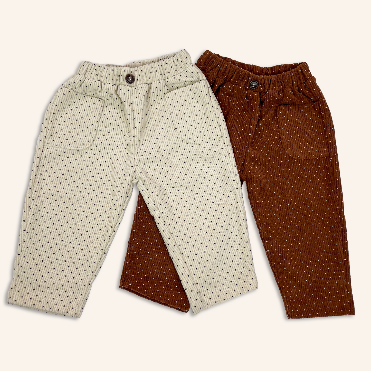 Beige and brown baby toddler corduroy trousers with all over polka dot print laid flat to show hip pockets and button at the front waistband