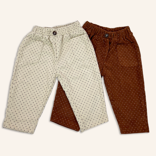 Beige and brown baby toddler corduroy trousers with all over polka dot print laid flat to show hip pockets and button at the front waistband