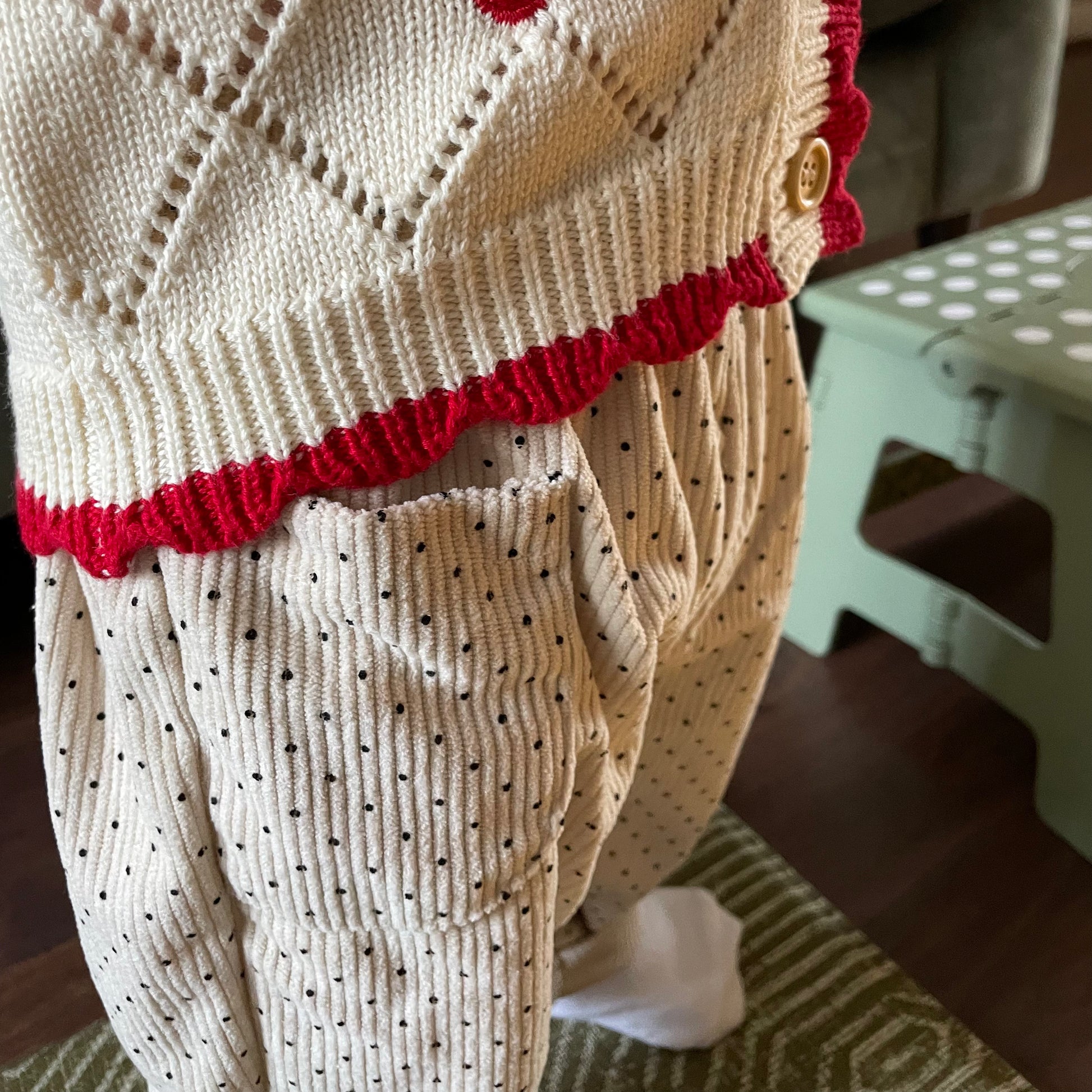 Close up view of cream polka dot baby corduroy trousers to show fabric in detail. Paired with cherry baby cardigan